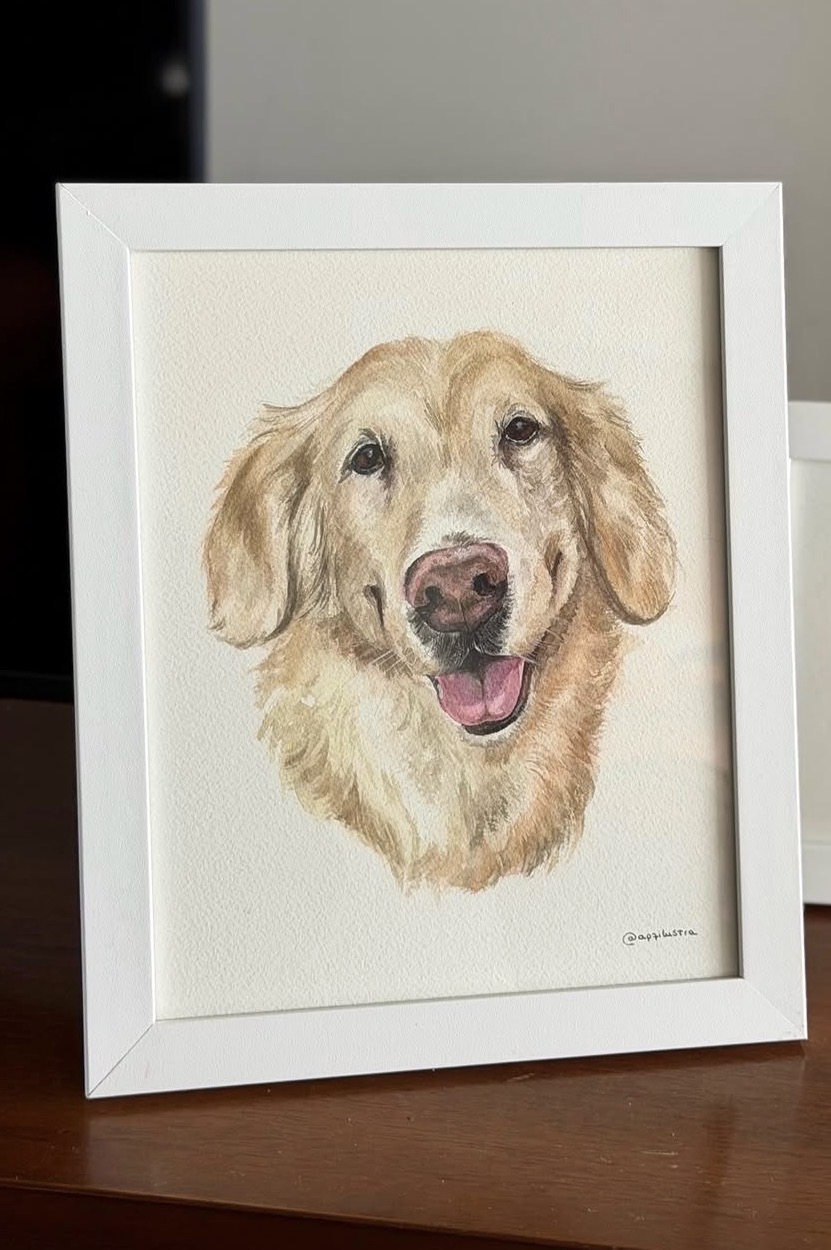 Aquarela de um golden retriever em moldura branca, apoiada sobre a mesa