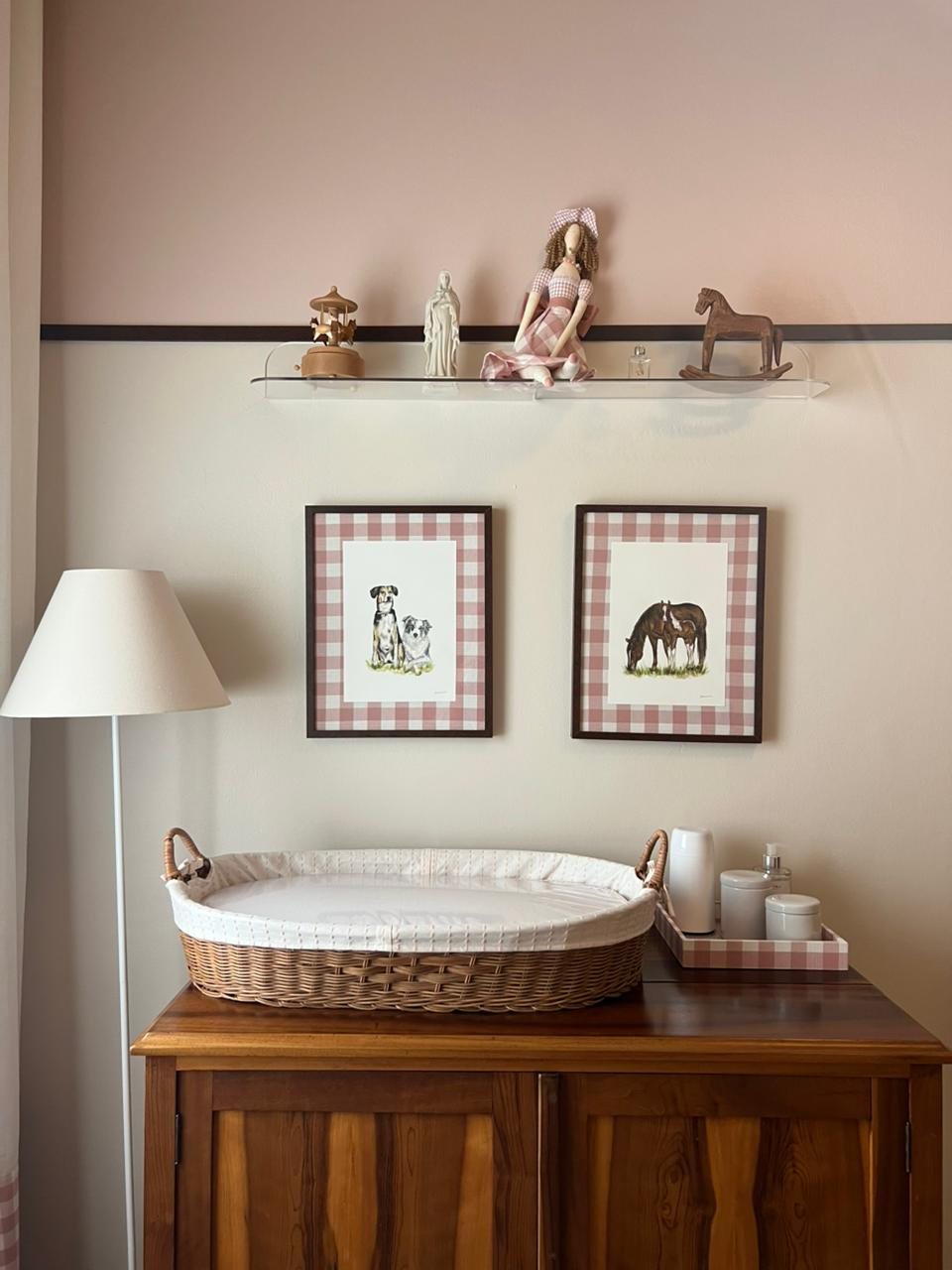 Dois quadros em aquarela na parede de um quarto, um de cachorros e outro de cavalos, em moldura xadrez rosa