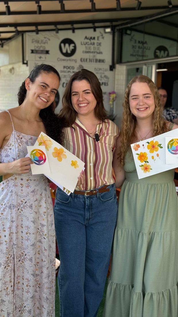Três alunas mostrando suas pinturas na primeira turma